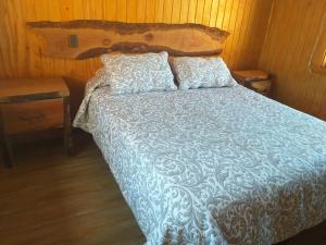 ein Bett mit einer blauen und weißen Bettdecke und Kissen in der Unterkunft CABAÑAS BOSQUE NEVADO in Malalcahuello