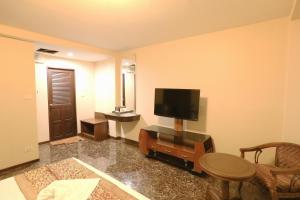 a living room with a television and a table and chairs at Katesiree House in Pattaya Central