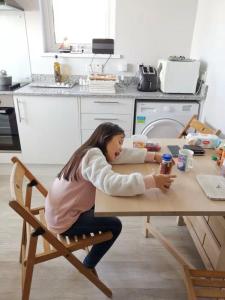 a woman sitting at a table in a kitchen at Berneray Otter Cottage in Berneray