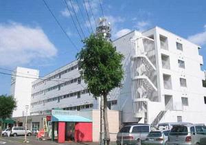 ein weißes Gebäude mit davor geparkt in der Unterkunft Mansion Pasture TSUKISAMU Fukuzumi in Sapporo