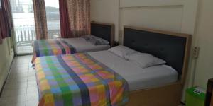 1 dormitorio con 2 camas y ventana en Enny's Guest House en Malang