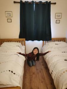 a little girl kneeling on the floor between two beds at Berneray Otter Cottage in Berneray