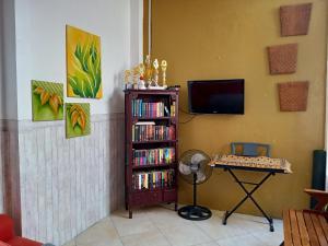 a living room with a tv and a book shelf with dvds at Kalandra Guest House in Ponorogo