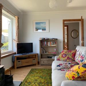 a living room with a couch and a television at Berneray Otter Cottage in Berneray