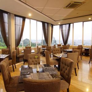 a restaurant with tables and chairs and large windows at Royal Hotel Bogor in Bogor