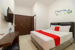 a bedroom with a large bed and a television at RedDoorz near Kejaksan Station Cirebon 2 in Cirebon