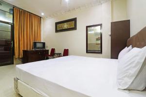 a bedroom with a large white bed and a television at Utama Syariah in Pekanbaru