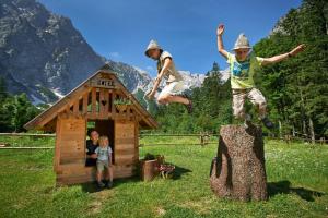 dos niños saltando de un tronco a una casa de perros en Holiday chalet "Alpine dreams" en Solčava