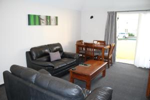 a living room with a leather couch and a table at Birchwood Manor in Invercargill