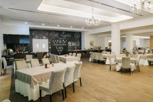 a restaurant with white tables and chairs and a chalkboard at President Hotel by Hrazdan Hotel CJSC in Yerevan