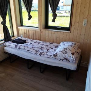 a bed in a room with two windows at Miðhvammur Farm Stay in Aðaldalur