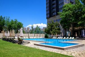 a swimming pool with chairs and umbrellas in a city at President Hotel by Hrazdan Hotel CJSC in Yerevan