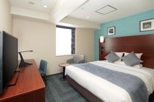 ein Hotelzimmer mit einem Bett, einem Schreibtisch und einem TV in der Unterkunft HOTEL MYSTAYS Yokohama in Yokohama