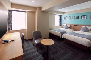 a hotel room with two beds and a desk at HOTEL MYSTAYS Yokohama in Yokohama