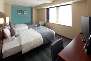 a hotel room with a bed and a television at HOTEL MYSTAYS Yokohama in Yokohama