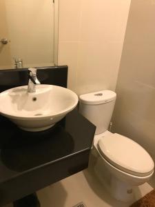 a bathroom with a white toilet and a sink at One Palm Tree Villas across NAIA-T3 in Manila