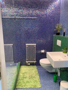 baño con aseo y pared de azulejos púrpura en 3-bedroom apartment with spectacular view, en Neuchâtel