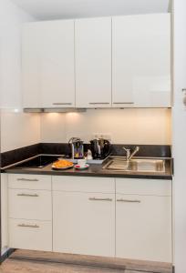 ベンスハイムにあるApartmenthaus Horsterの白いキャビネットとシンク付きのキッチン