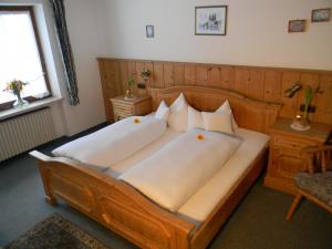 ein Schlafzimmer mit einem großen Holzbett mit weißen Kissen in der Unterkunft Landhaus Spielmannsau in Oberstdorf