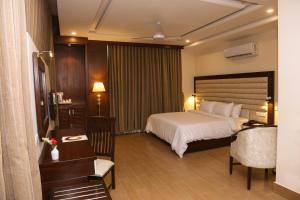ラヒムヤルカーンにあるHotel One Rahim Yar Khan Club Roadのベッド、デスク、椅子が備わるホテルルームです。