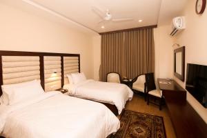 a hotel room with two beds and a television at Hotel One Rahim Yar Khan Club Road in Rahimyar Khan