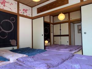 東京にあるKamata Annの紫のシーツが備わる客室内のベッド2台