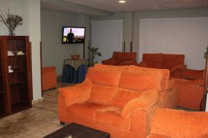 uma sala de estar com mobiliário laranja e uma televisão de ecrã plano em Hotel Peña Escrita em Fuencaliente