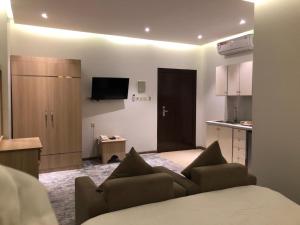 a living room with a couch and a kitchen at Hala Onaizah in Unayzah