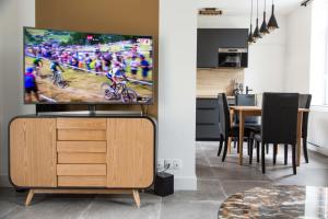 Il comprend un salon doté d'une télévision et d'une table avec des chaises. dans l'établissement Gîtes de La Vesée, à La Chapelle dʼArmentières