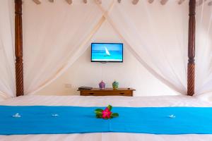 a bedroom with a bed with a tv on the wall at Diani Sea Lodge - All Inclusive in Diani Beach