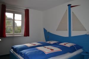 a bedroom with two beds with blue sheets and a window at Apartments im Sössaarep's Hüs in Nebel