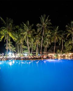 a large pool with palm trees and a beach at night at Diani Sea Lodge - All Inclusive in Diani Beach
