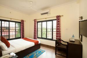 a bedroom with a bed and a desk and two windows at Hotel The Holy Birth in Rummindei