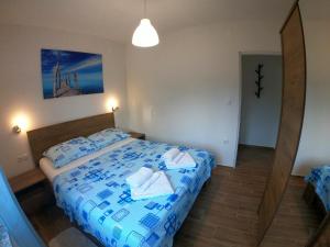 a bedroom with a bed with blue and white sheets at Apartmani Zekic in Lopar