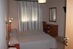 1 dormitorio con 2 camas, escritorio y ventana en Hotel Peña Escrita, en Fuencaliente