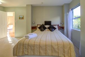 1 dormitorio con 1 cama con edredón amarillo y ventana en Journeys end, en Raglan