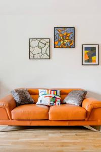 an orange couch in a living room with four pictures at Passion et détente by UTA HOUSE in Saint-Denis