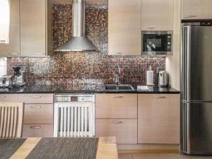 a kitchen with wooden cabinets and a stainless steel refrigerator at Holiday Home Villa illi by Interhome in Tahkovuori
