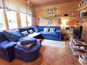 a living room with a blue couch and a tv at Holiday Home Alppitalo b by Interhome in Ylläsjärvi