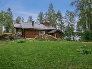 een blokhut in een veld van groen gras bij Holiday Home Hiidenlinna by Interhome in Pitkälahti