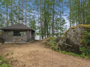 een kleine hut in het bos naast een grote rots bij Holiday Home Hiidenlinna by Interhome in Pitkälahti