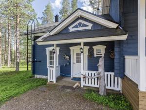 uma casa azul com um alpendre e uma porta branca em Holiday Home Komsikko b by Interhome em Äkäslompolo