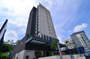a tall white building with a green sign on it at ibis Styles Kuala Lumpur Sri Damansara in Petaling Jaya
