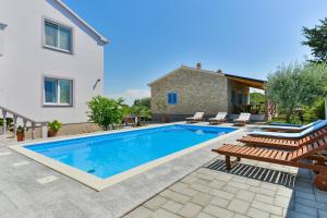 einen Pool mit Stühlen und ein Haus in der Unterkunft Apartments Crno in Zadar