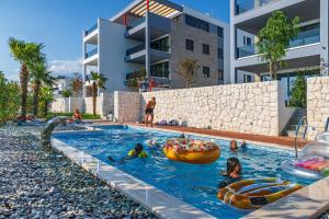 un grupo de niños jugando en una piscina en un edificio en VIPo Prestige Apartments en Podstrana