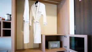 a white robe hanging on a wall next to a tv at Picnic Hotel Bangkok - Rang Nam in Bangkok