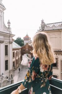 a woman standing on a balcony looking at a city at H15 Hotel Francuski in Krakow