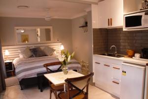 a bedroom with a bed and a table and a kitchen at Paperbark Bed & Breakfast in Brisbane