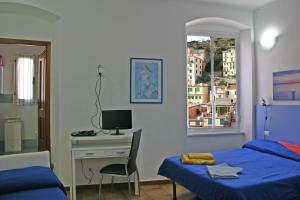 een slaapkamer met 2 bedden en een bureau met een computer bij Casa il Gabbiano in Riomaggiore