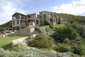 a large stone house on top of a hill at Agulhas Country Lodge in Agulhas